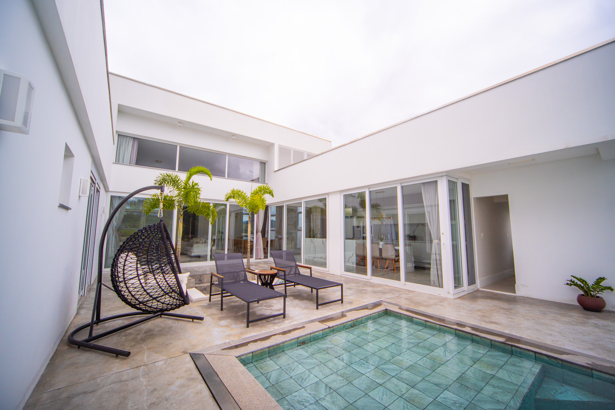Pátio de residência contemporânea com piscina, portas de vidro e áreas de convívio.